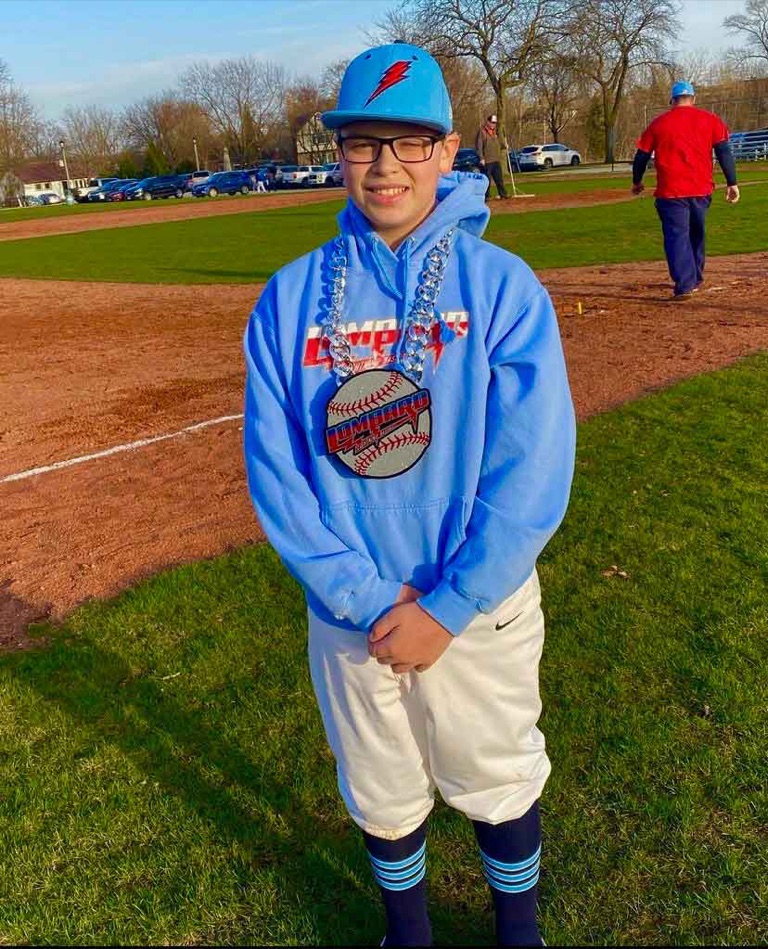 Youth baseball player wearing a custom chain on the field sideline