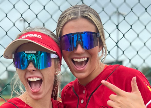 Two girls having fun wearing ThrillVision sports sunglasses during a break between innings on the field.