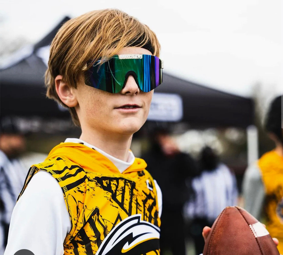 Young football player wearing ThrillVision sports sunglasses, ready for action on the field.